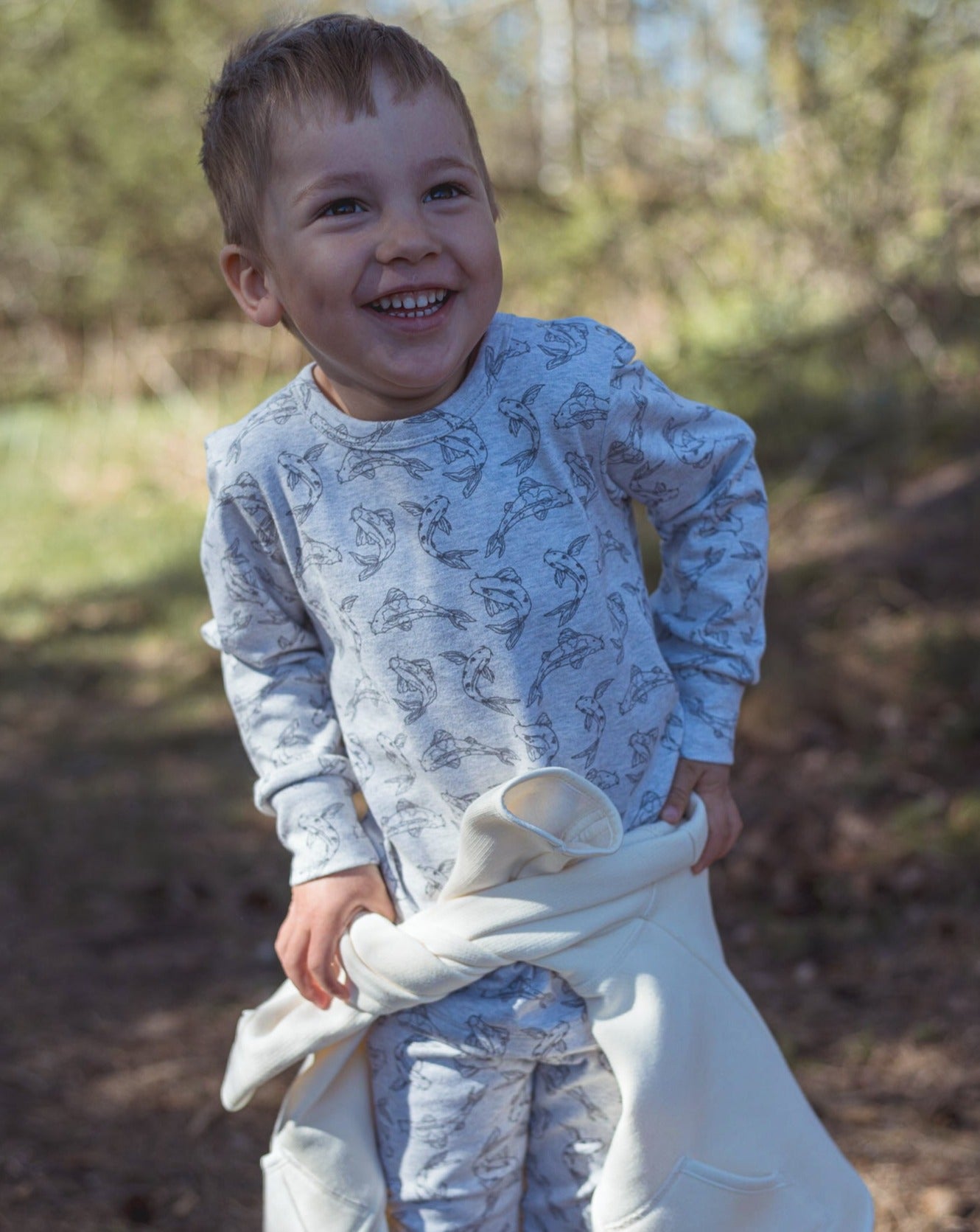 Allover printed long sleeve with our signature Koi fish print in grey mélange. With round neck, press buttons at shoulder. Extra length added to the body for a loose and relaxed look.