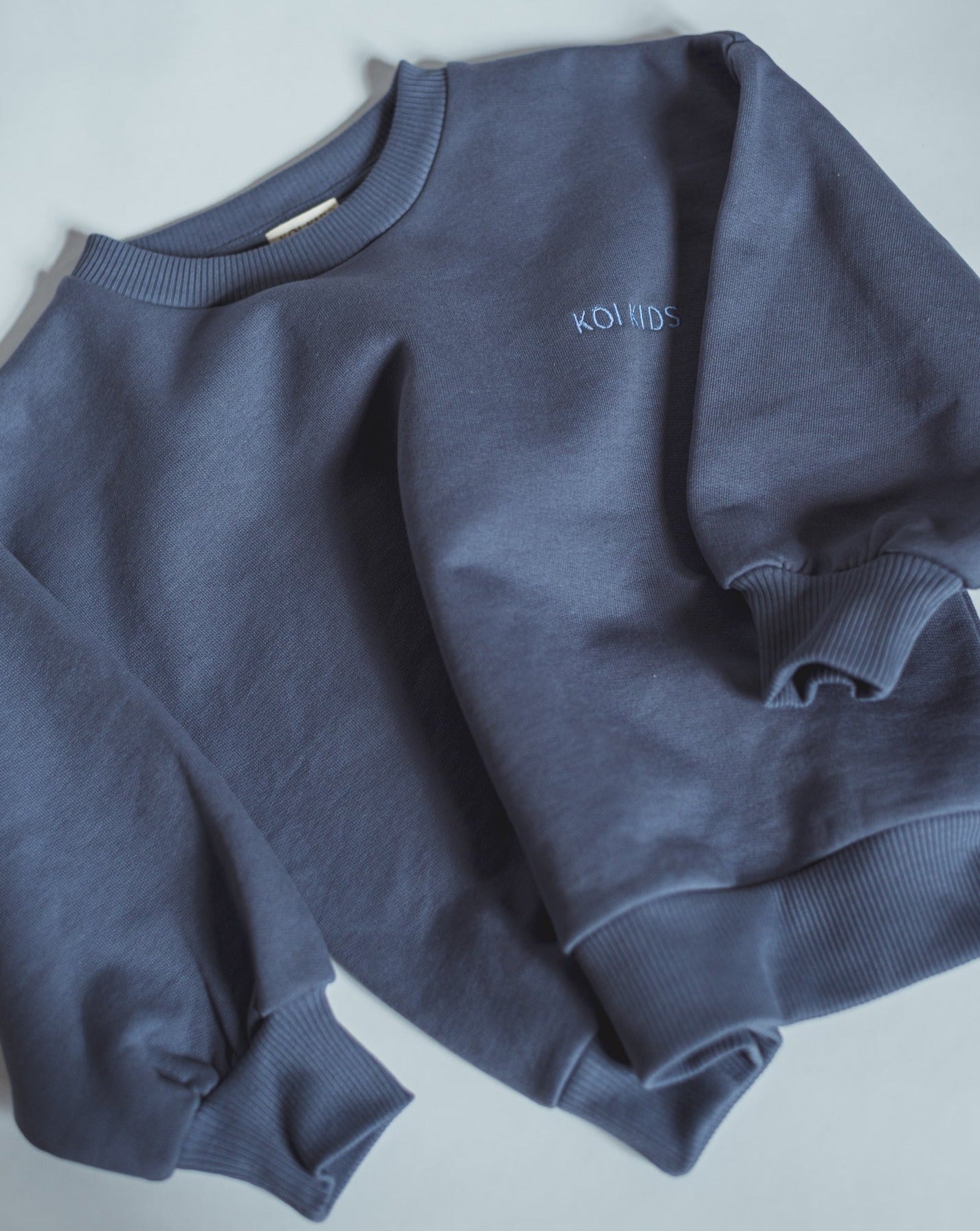 Denim blue sweatshirt with light blue logo embroidery, dropped shoulders and foldable cuffs with an oversized fit.