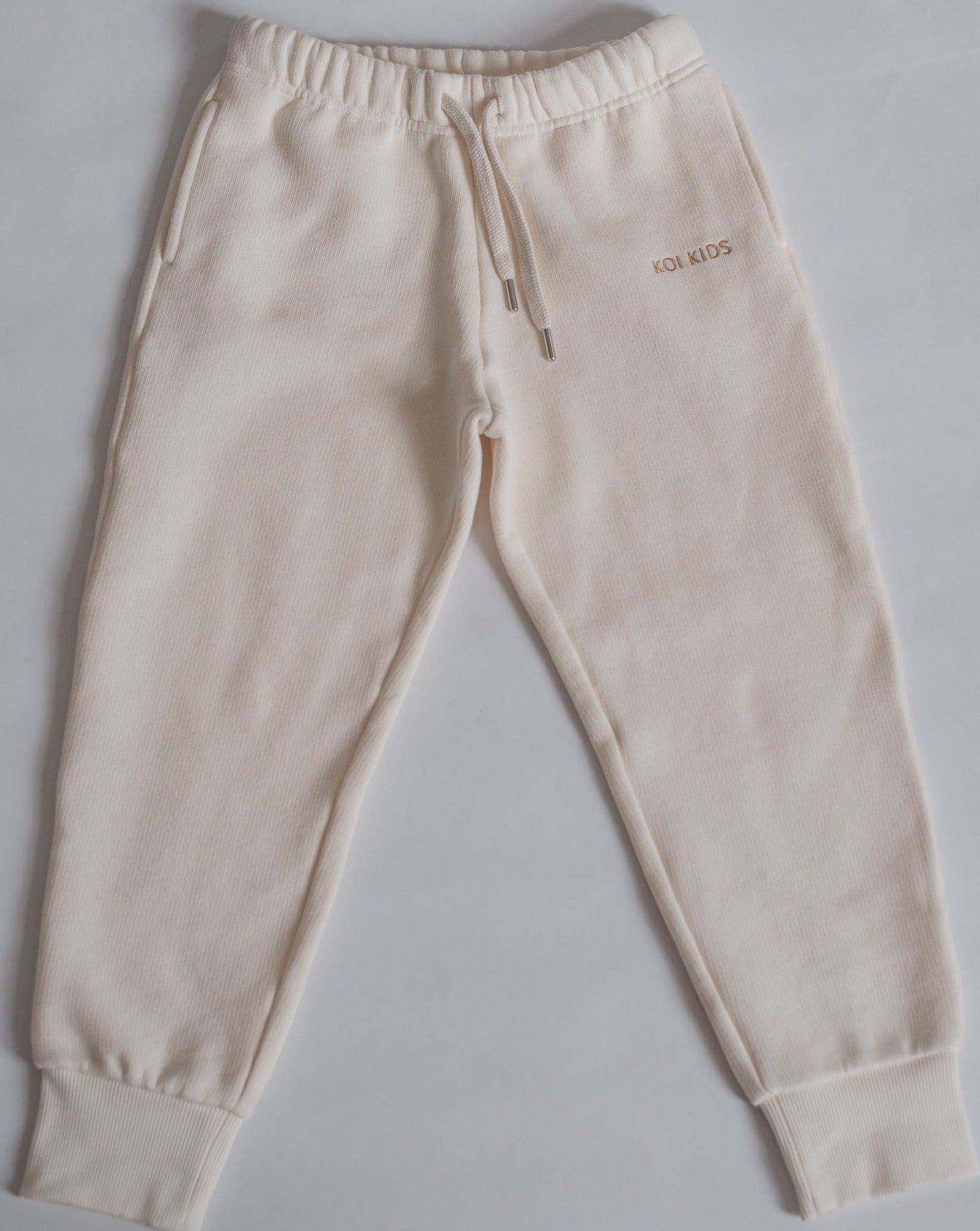 Offwhite sweatpants with a drawstring elasticated waist, light brown logo embroidery, side pockets and ribbed cuffs.