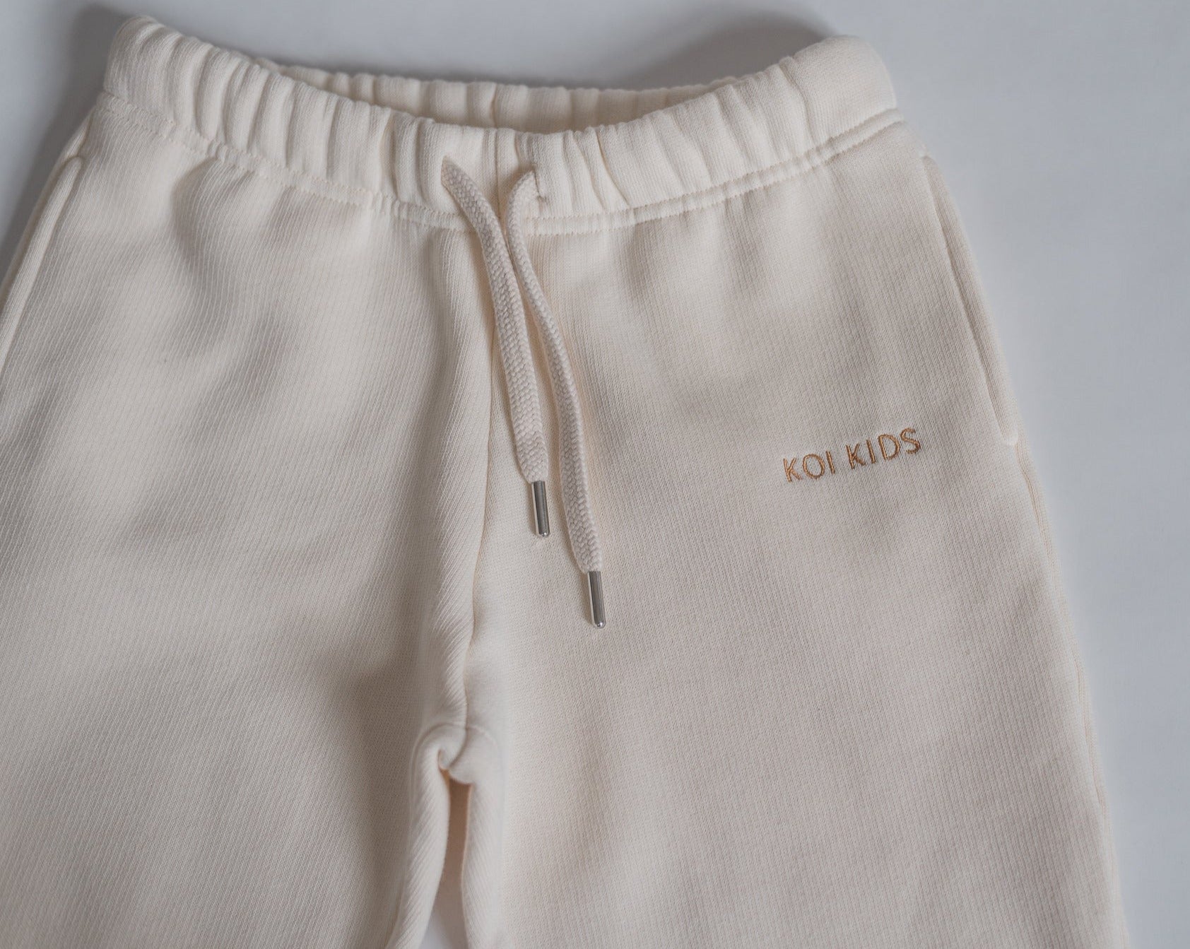 Offwhite sweatpants with a drawstring elasticated waist, light brown logo embroidery, side pockets and ribbed cuffs.