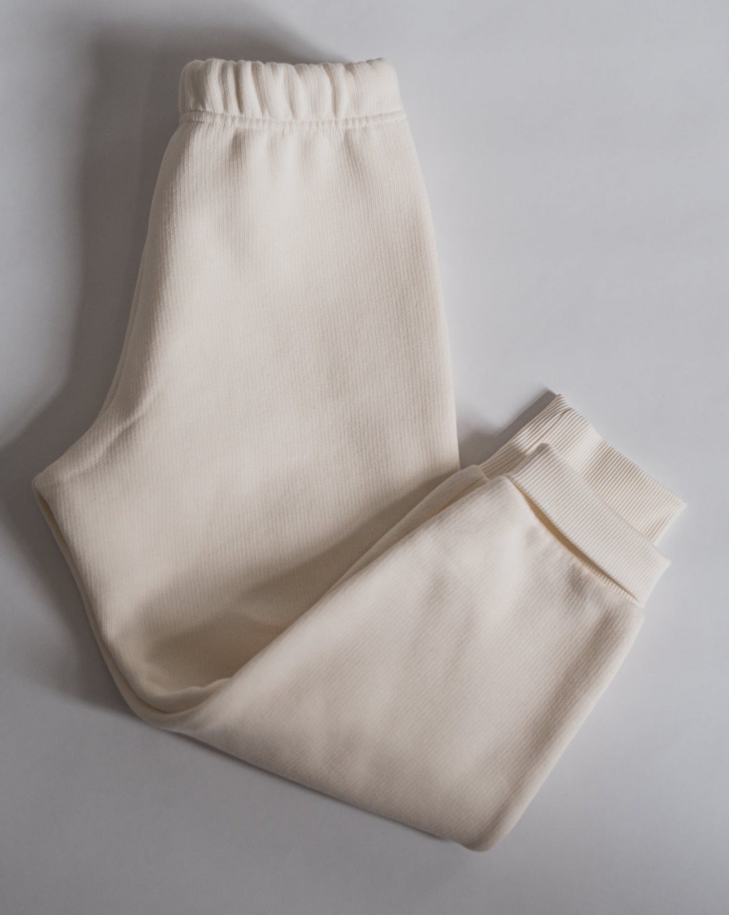 Offwhite sweatpants with a drawstring elasticated waist, light brown logo embroidery, side pockets and ribbed cuffs.