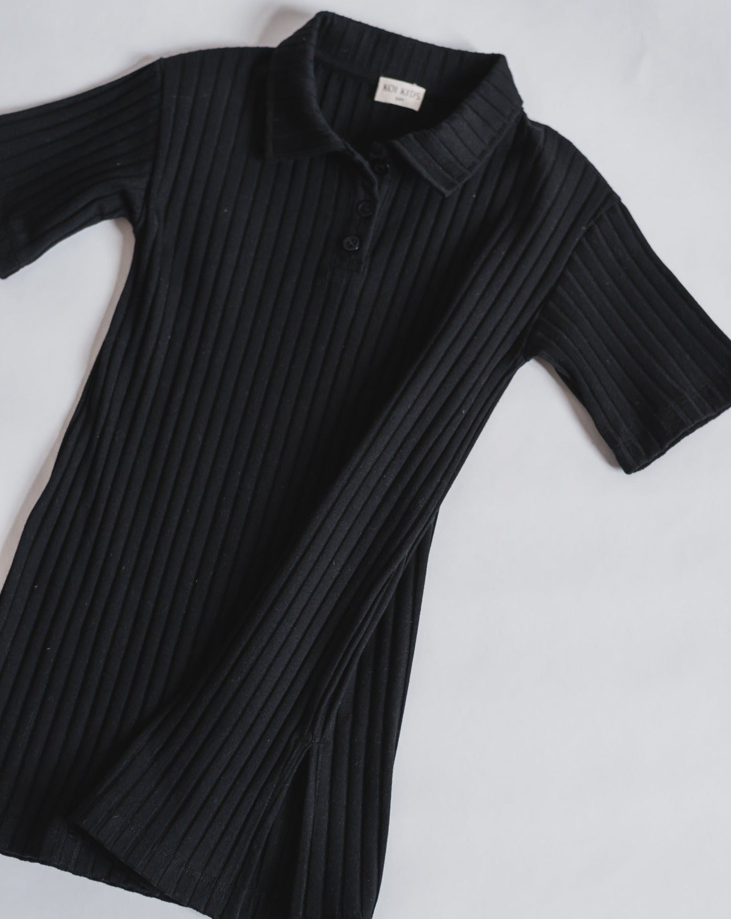 Black midi length shirt dress in a ribbed jersey fabric. Relaxed fit with elbow length sleeves and a collar neckline with 3 buttons and split hem in both sides.