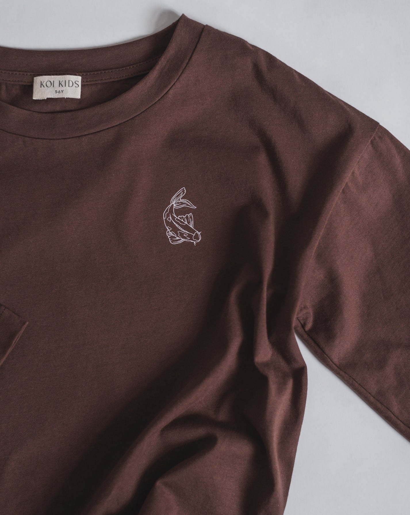 Brown oversized organic cotton long sleeve, with round neck, contrast colored Koi fish print at chest. A boxy fit for a loose and relaxed look.
