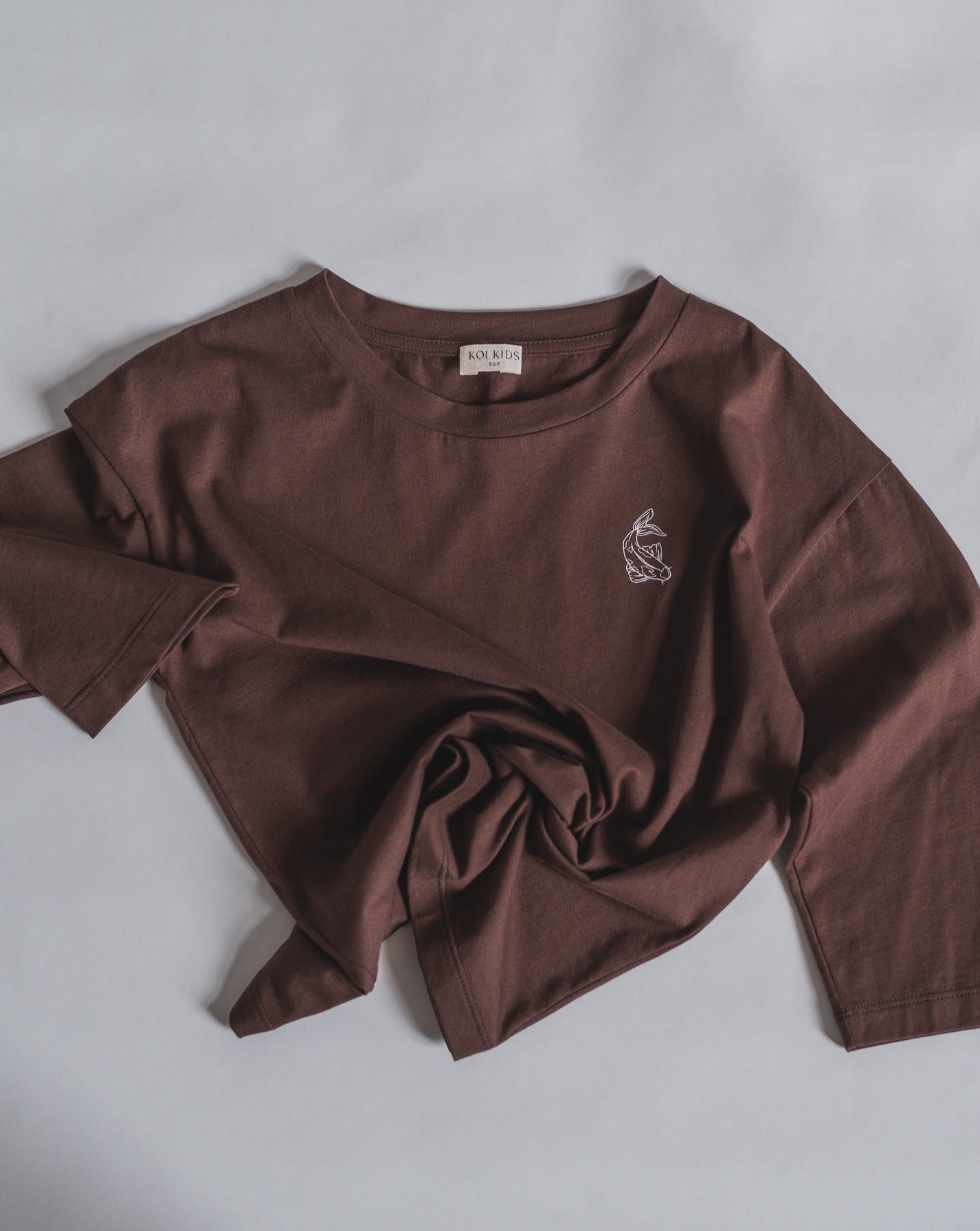 Brown oversized organic cotton long sleeve, with round neck, contrast colored Koi fish print at chest. A boxy fit for a loose and relaxed look.