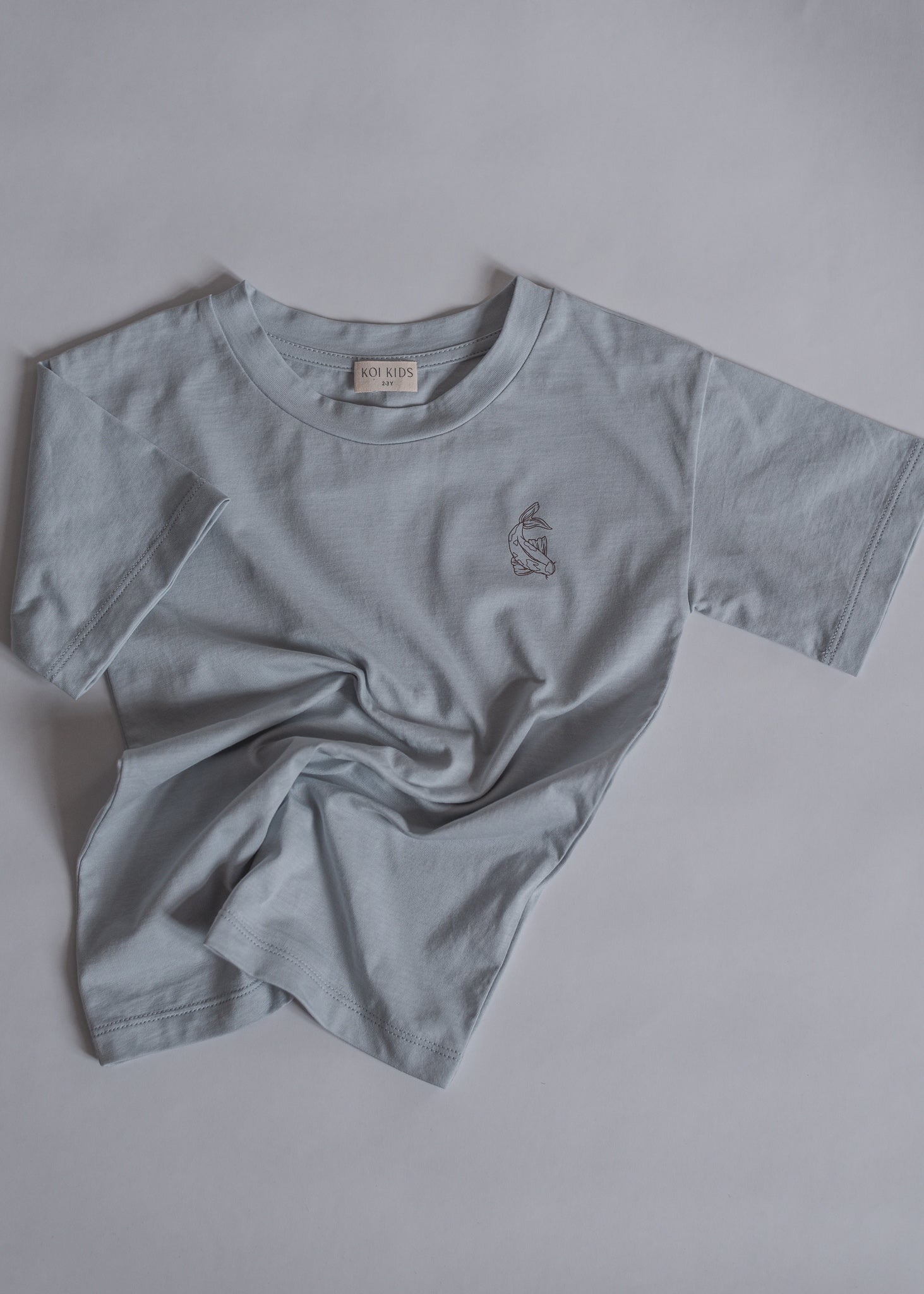 Light blue oversized organic cotton t-shirt, with round neck, contrast colored Koi fish print at chest. A boxy fit for a loose and relaxed look.
