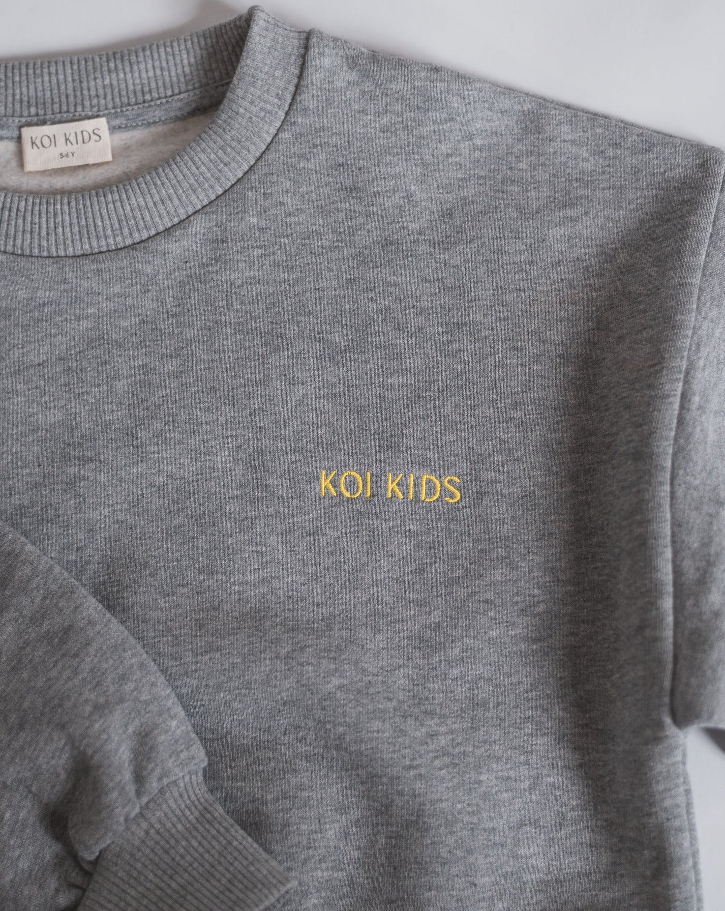 Grey mélange sweatshirt with yellow logo embroidery, dropped shoulders and foldable cuffs with an oversized fit.