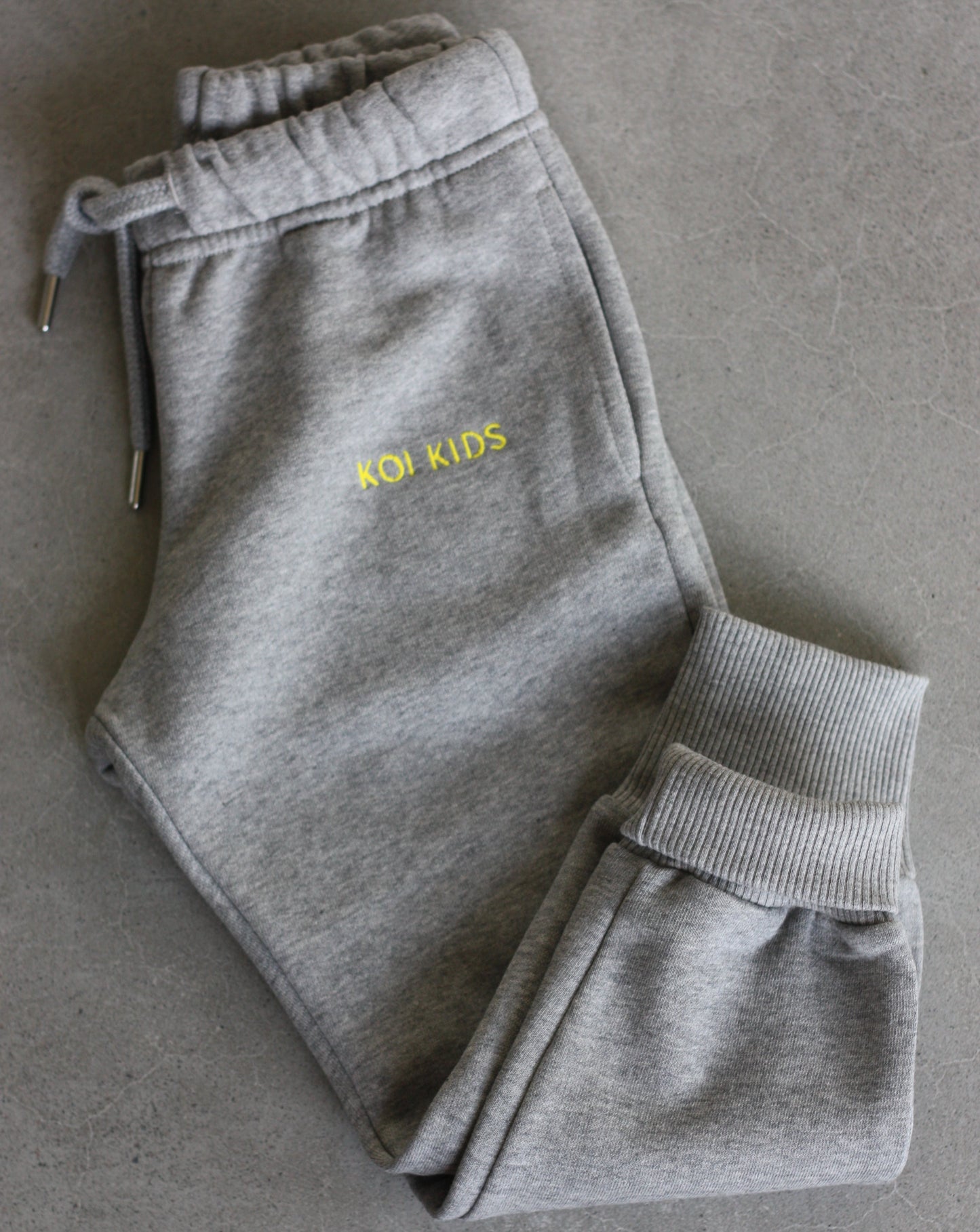 Grey mélange sweatpants with a drawstring elasticated waist, yellow logo embroidery, side pockets and ribbed cuffs.