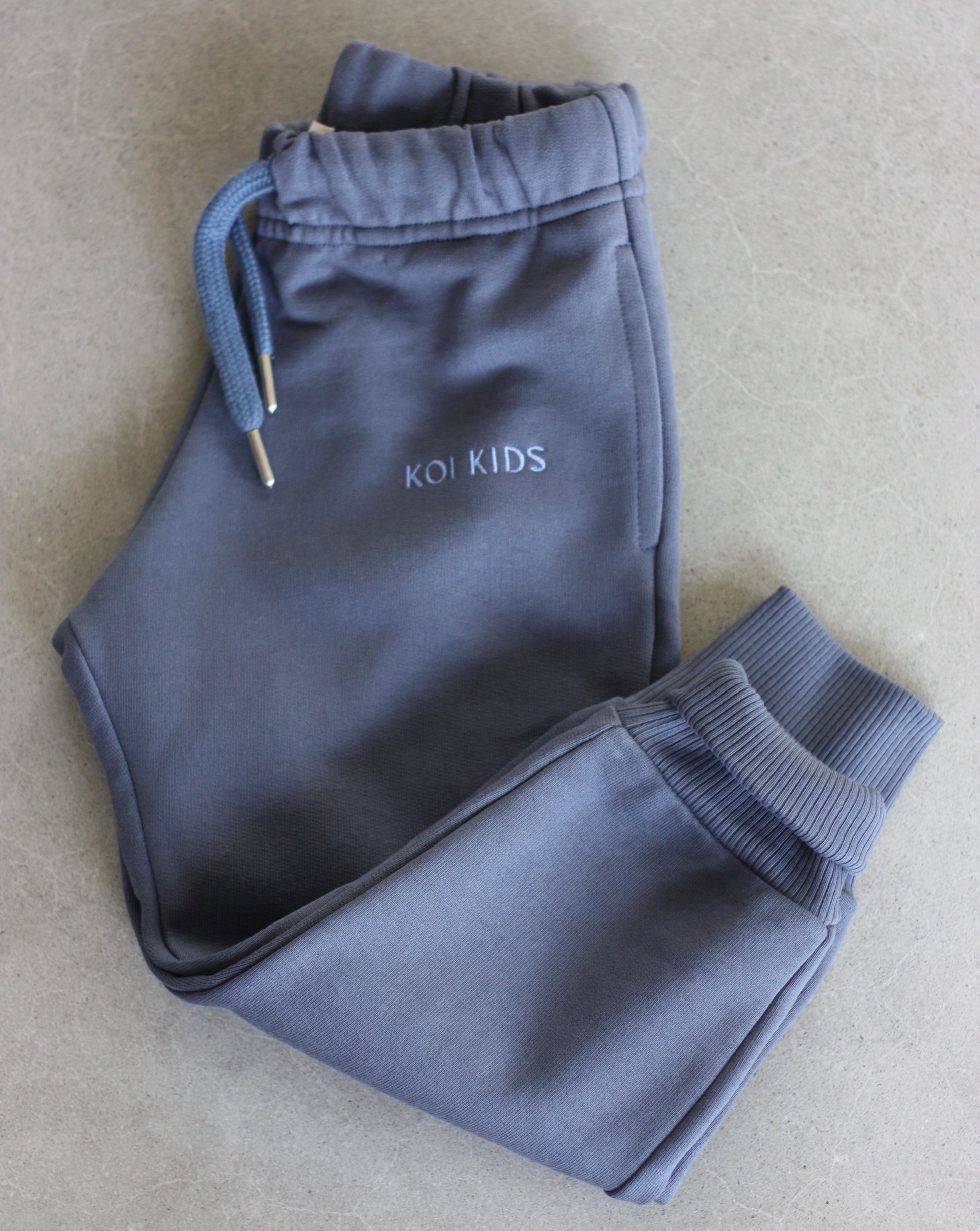 Denim blue sweatpants with a drawstring elasticated waist, light blue logo embroidery, side pockets and ribbed cuffs.