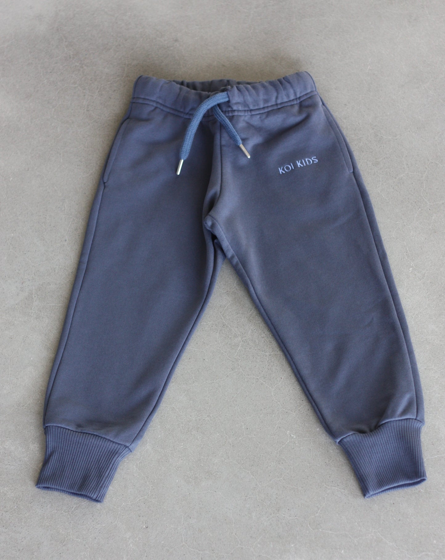 Denim blue sweatpants with a drawstring elasticated waist, light blue logo embroidery, side pockets and ribbed cuffs.