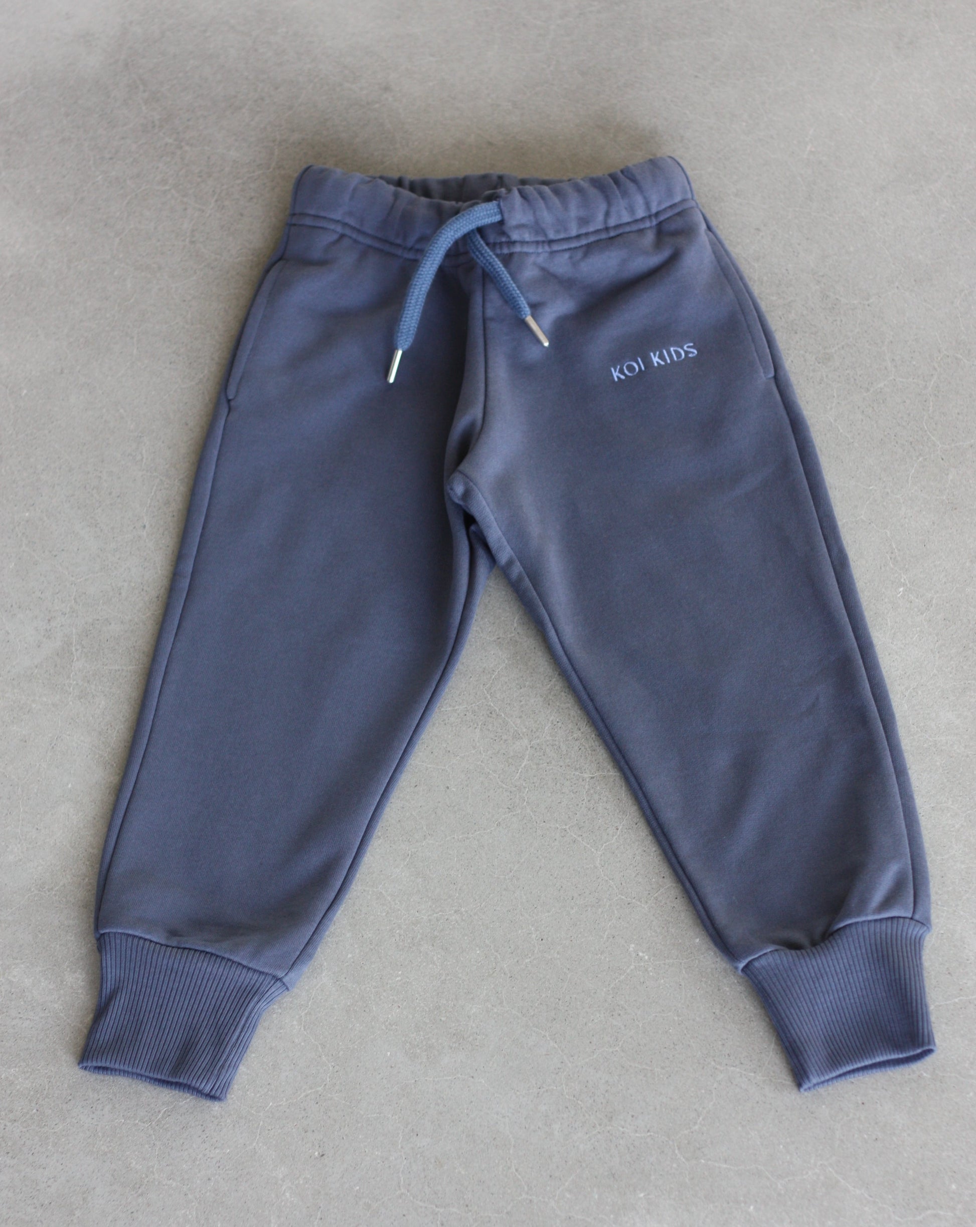 Denim blue sweatpants with a drawstring elasticated waist, light blue logo embroidery, side pockets and ribbed cuffs.